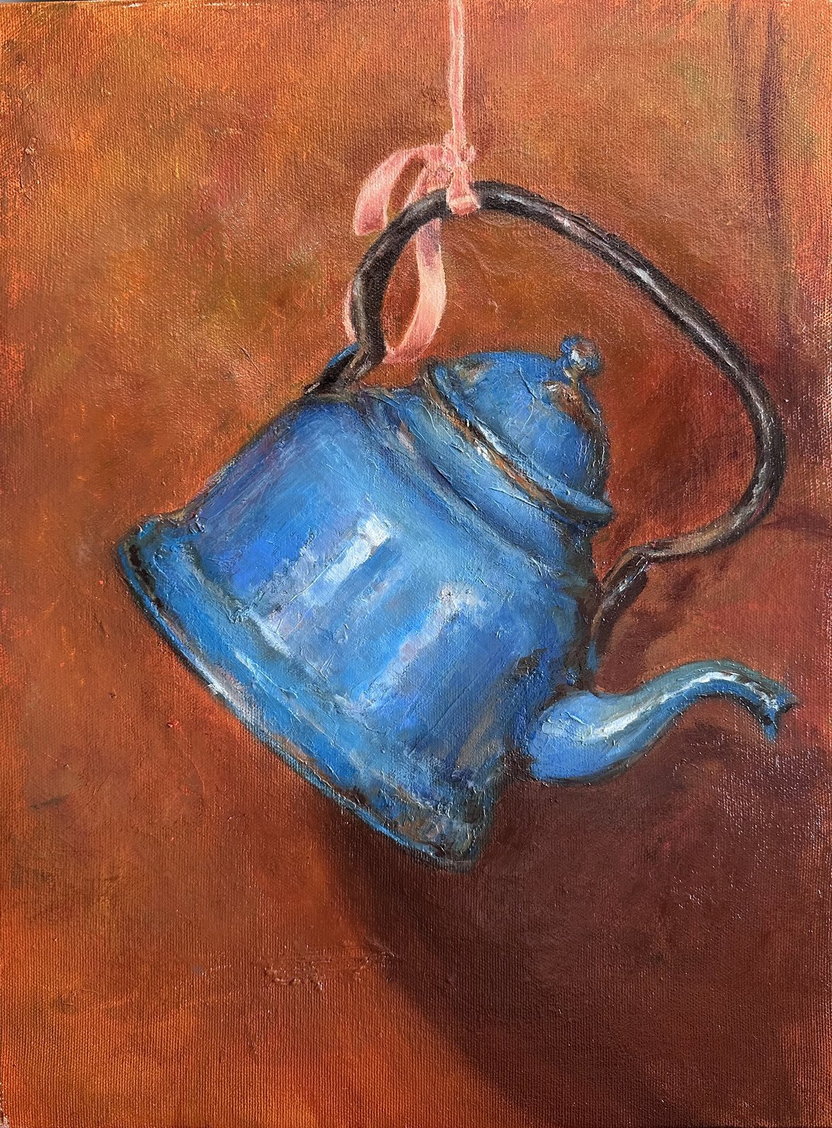 A blue enamel teapot hanging by a pink ribbon against a copper background