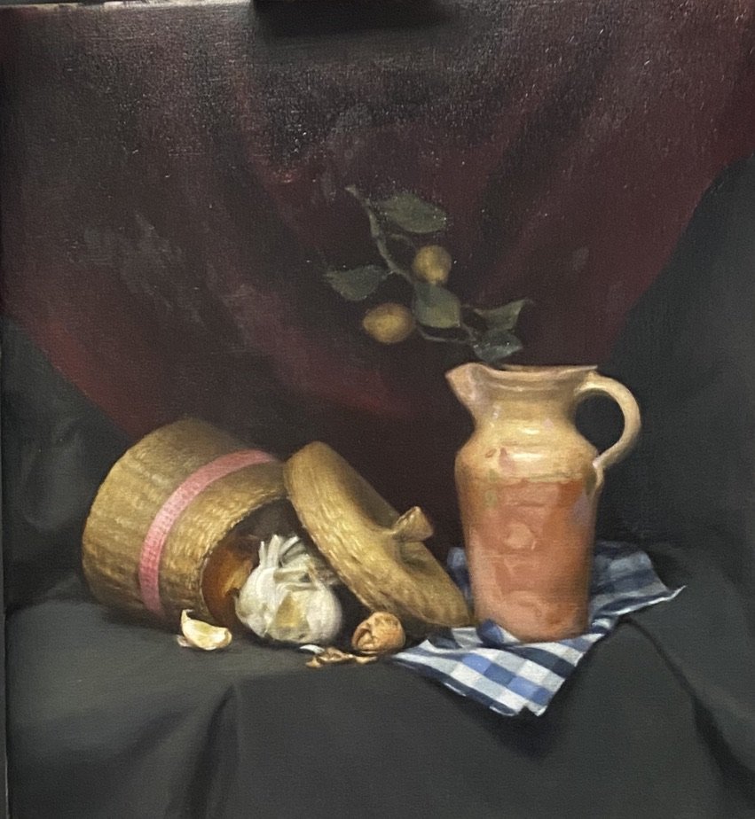 Still life with a wicker basket, garlic, walnuts, and a terracotta jug on a blue checkered cloth