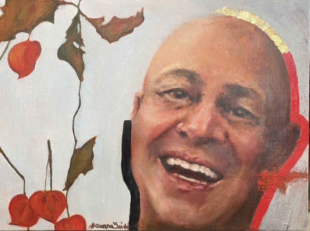 A laughing bald man with a gold-leaf and red halo behind his head, beside a branch of physalis fruit